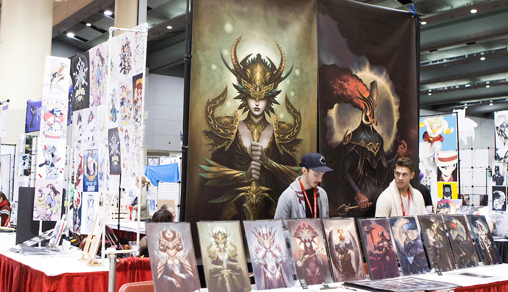 Two men standing at a booth selling art at Fan Expo