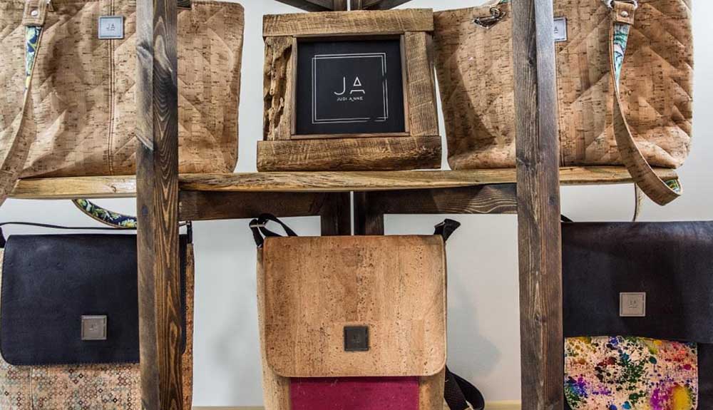 Handcrafted bags sit on a retail shelf made of wood