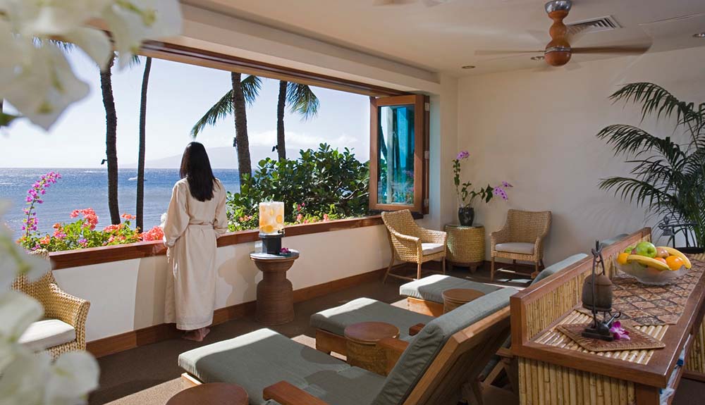 A woman in a spa robe gazes out at the beautiful beach view from the bar and lounge area at the Hyatt Regency Maui Resort and Spa