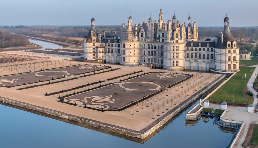 The sprawling Chateau de Chambord stands in the distance with an impeccably kept garden in the foreground
