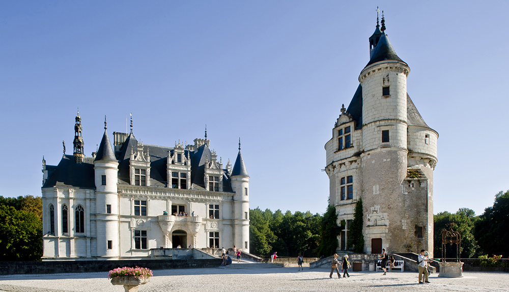 People walking outside the tall buildings of Chateau de Chenonceau