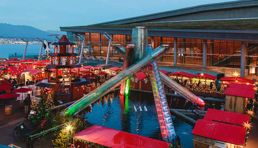 A sculpture sits on top of a fountain at the Vancouver Christmas Market surrounded by vendors