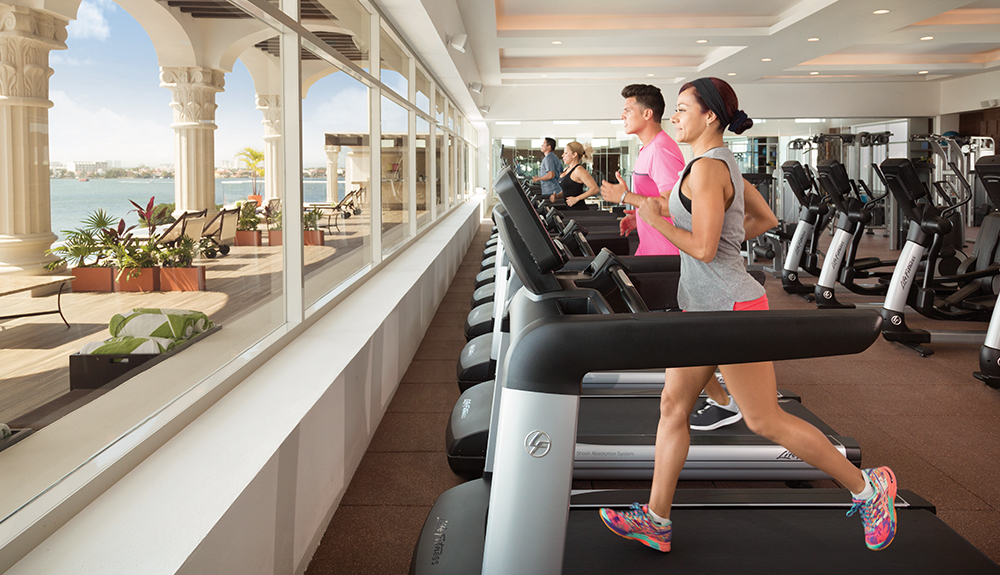 Woman and man running on the treadmill at the indoor gym of the resort