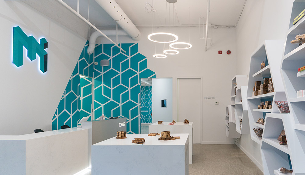 Inside the Museum of Illusions with white tables and custom shelves with neat illusion related things on display