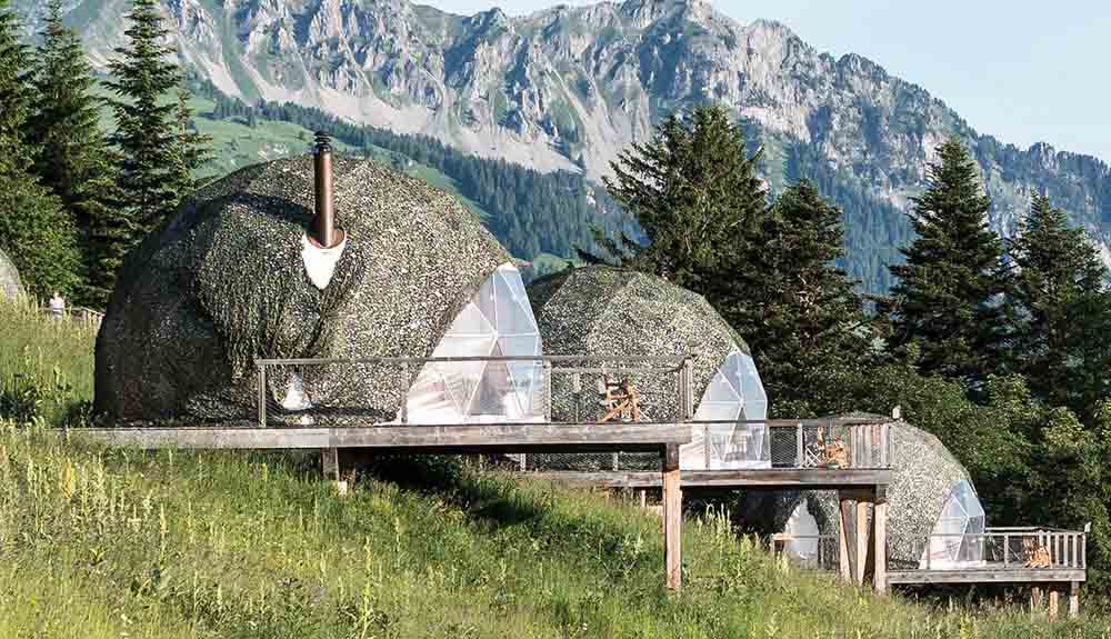 Three charming eco-luxury pods on a hill with balconies featuring mountains in the background