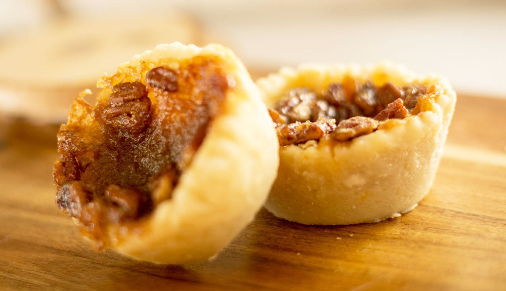 Two beautiful flakey butter tarts with nuts in them