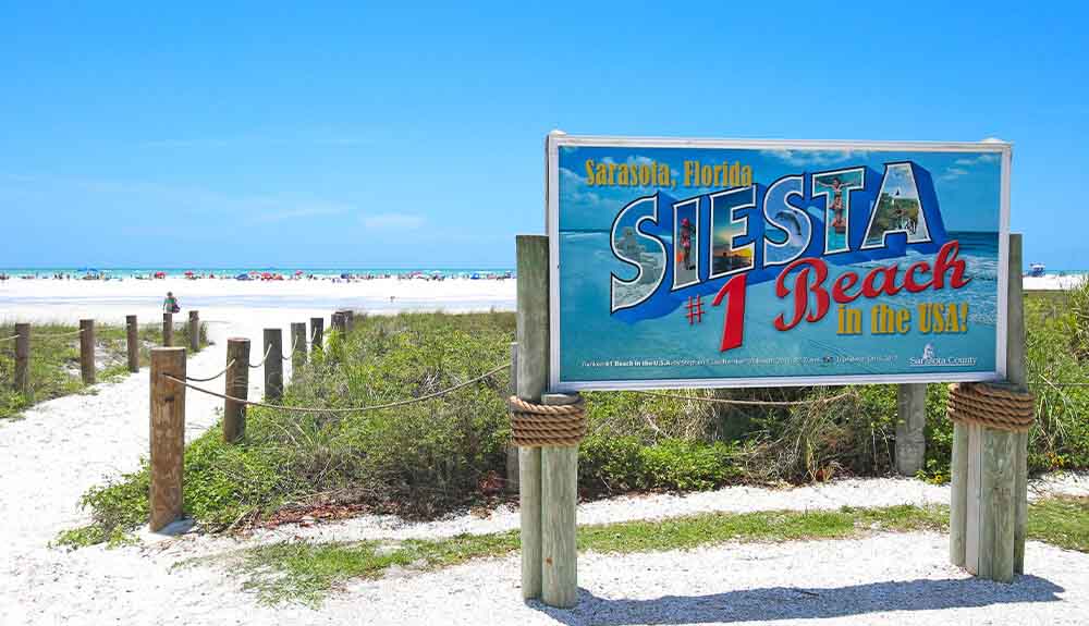 A sign welcomes visitors to Siesta Beach in Sarasota, Florida