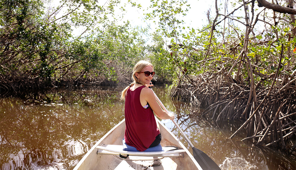 Woman sitting in front of canoe going through swamp in Florida