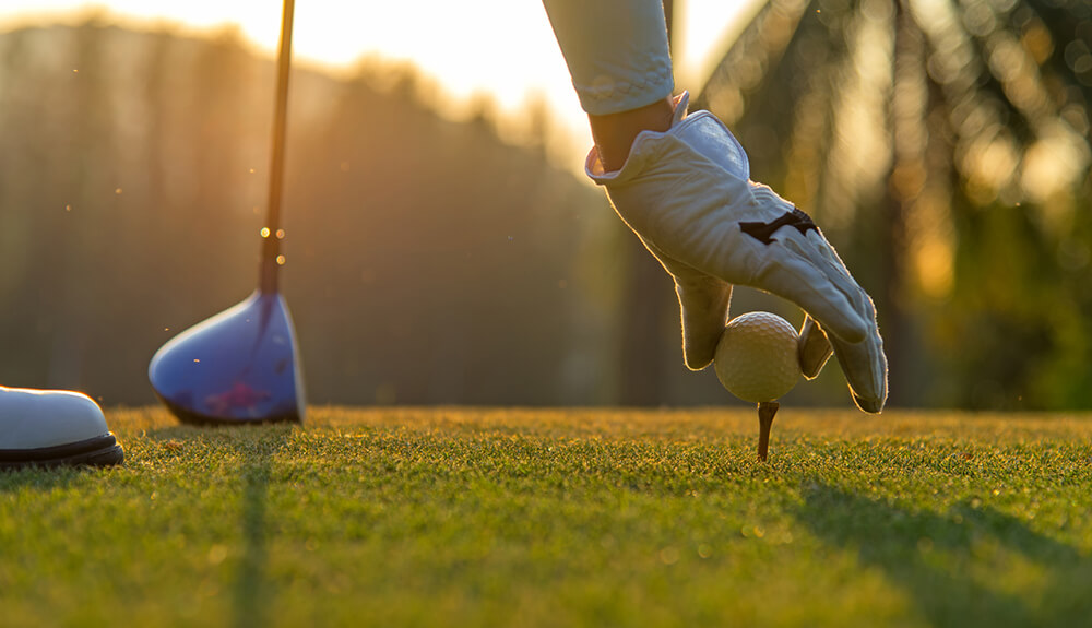 Hand placing golf ball on tee