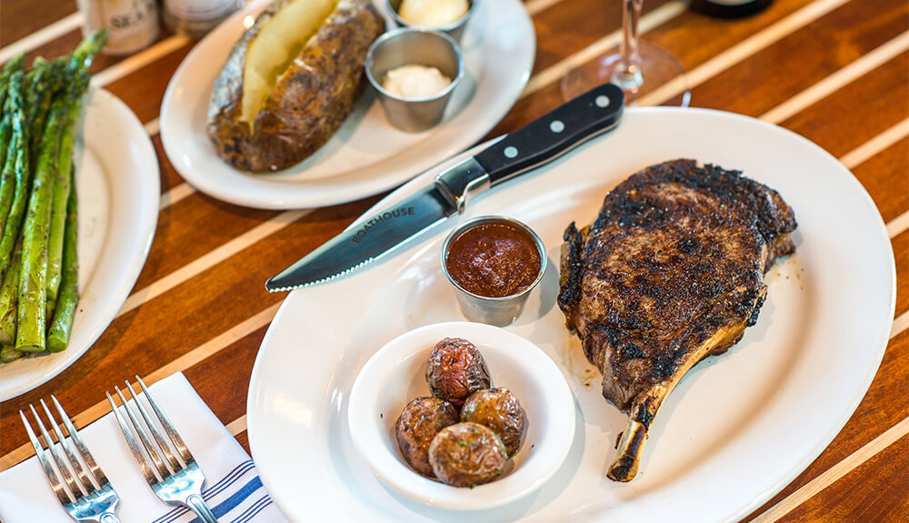 Steak and baked potato on plates on restaurant table
