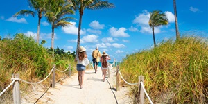 Group of people walking on path through dunes to beach in Florida