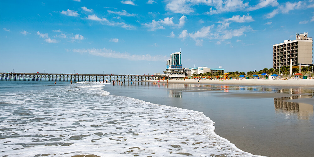 Sunny day on shore of Myrtle Beach with pier in the distance