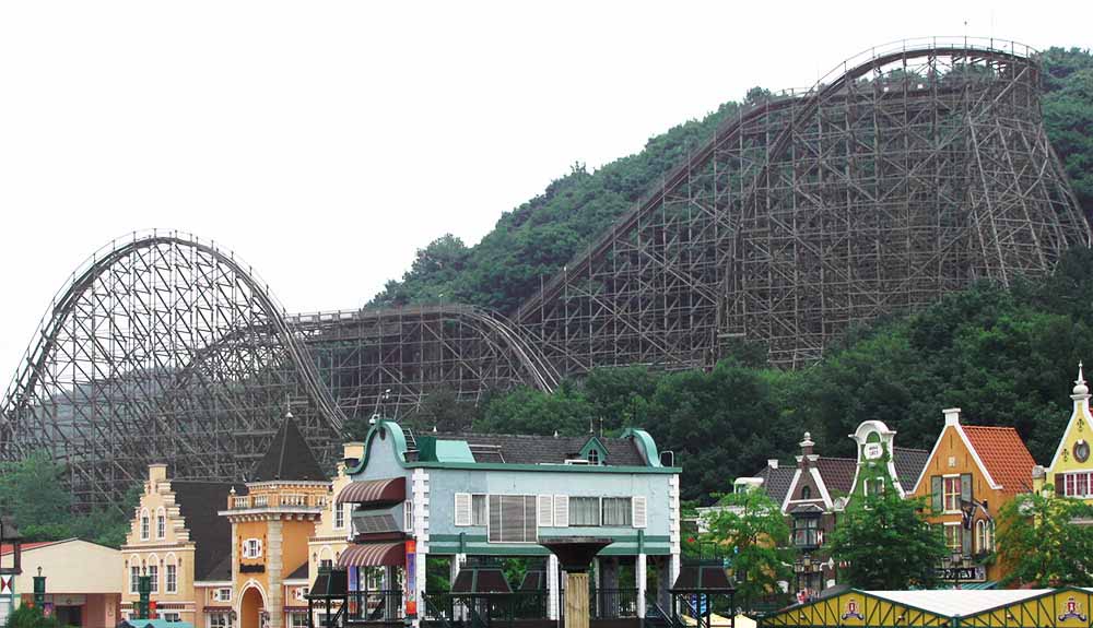 A view of a the T Express wooden roller coaster behind cute theme park buildings