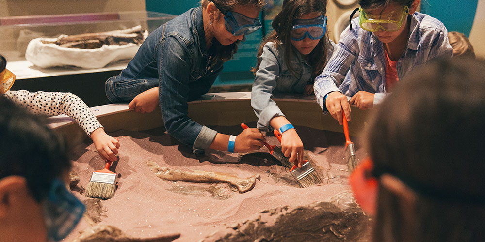 A group of small children play at the palaeontology exhibit at the Royal Ontario Museum