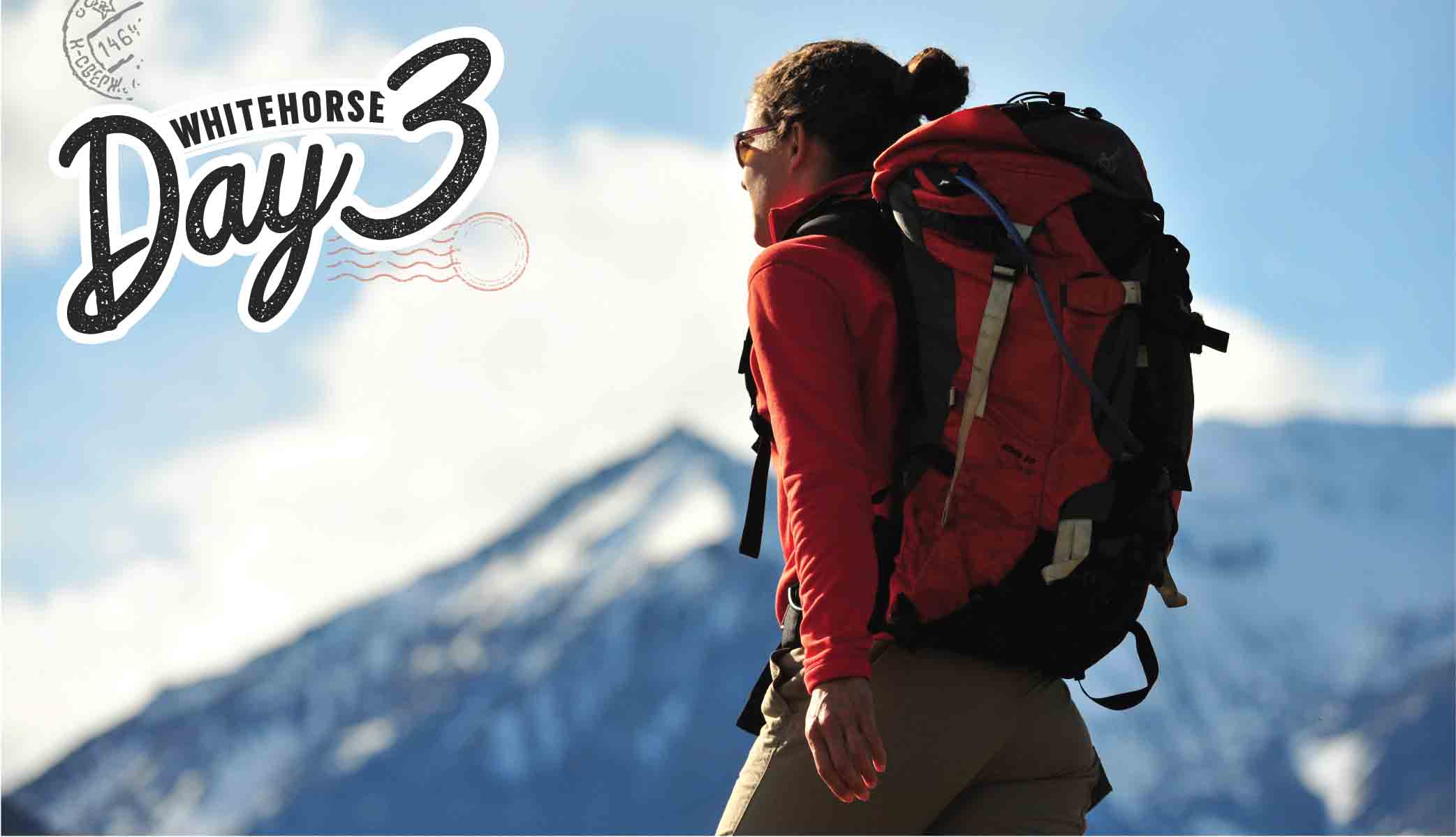 Woman wearing a backpack walk with mountains in the background