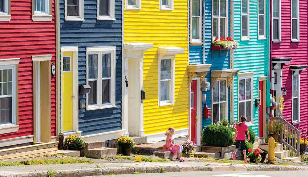 Red, blue, yellow, light blue and pink buildings line a street with iconic colourful houses in St. Johns