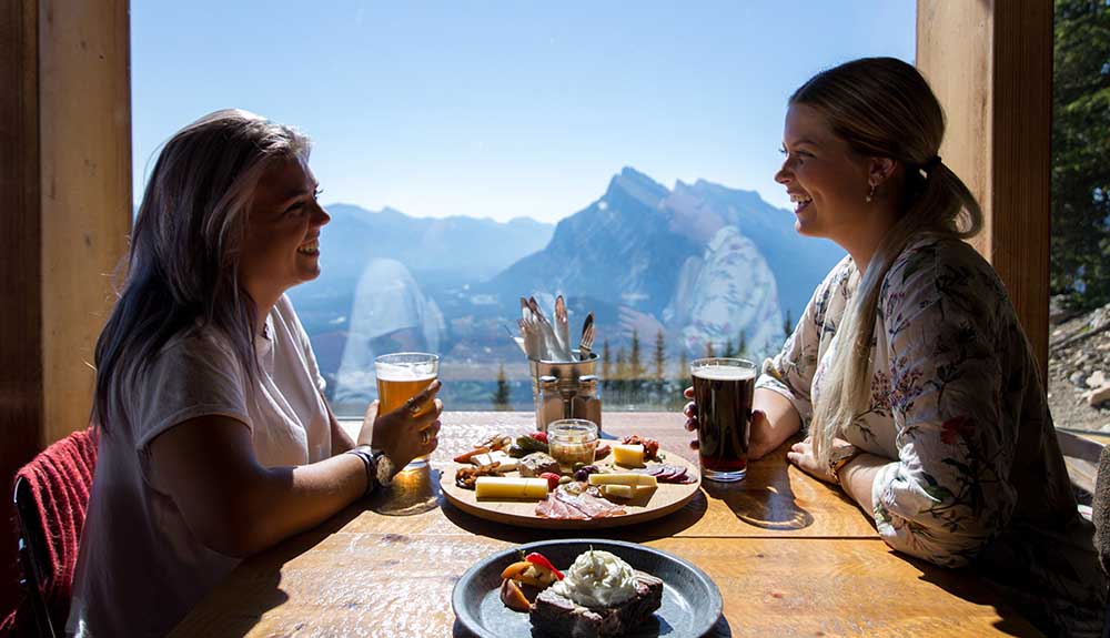 Two women dine at Cliffhouse Bistro at a table that looks out at the mountains.