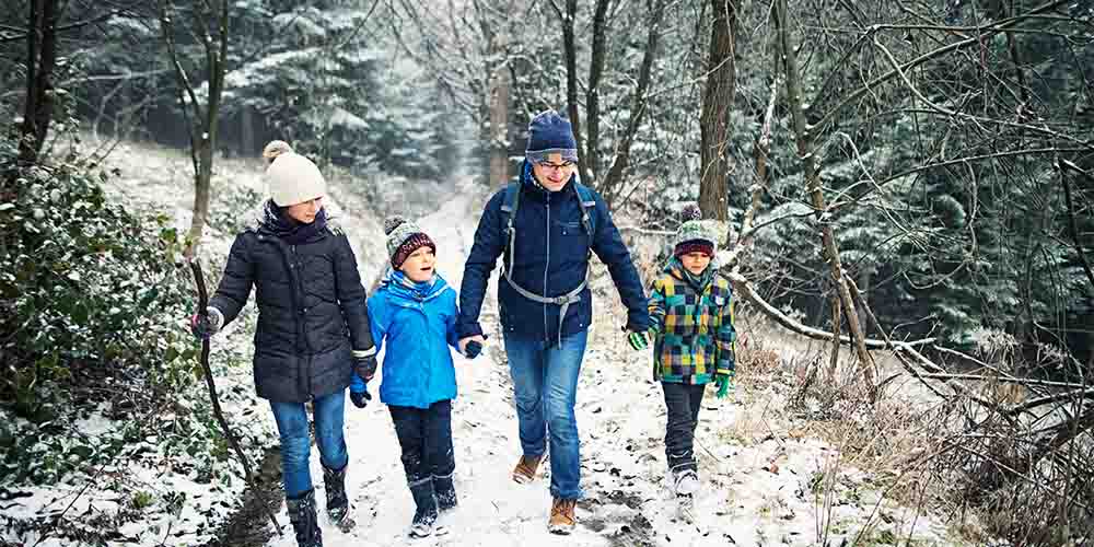 A family walks along a nature trail in the winter