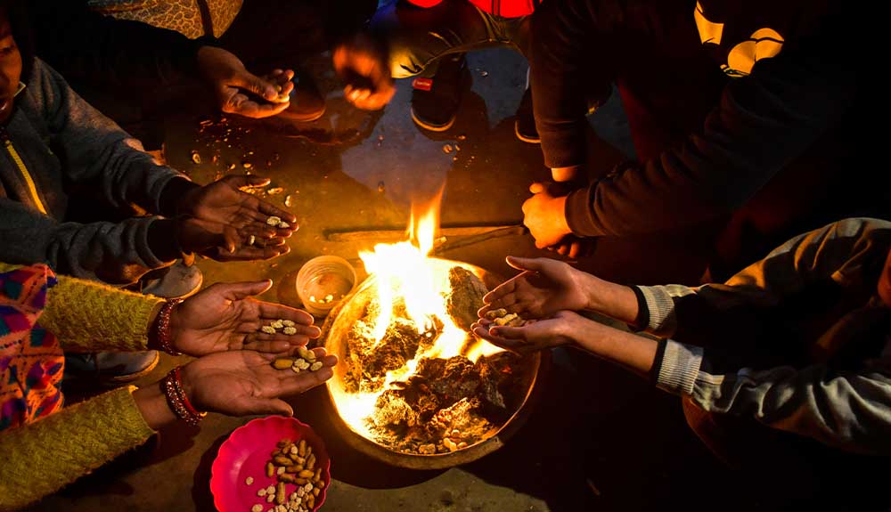 Hands are shown held out towards a bowl of fire on a table