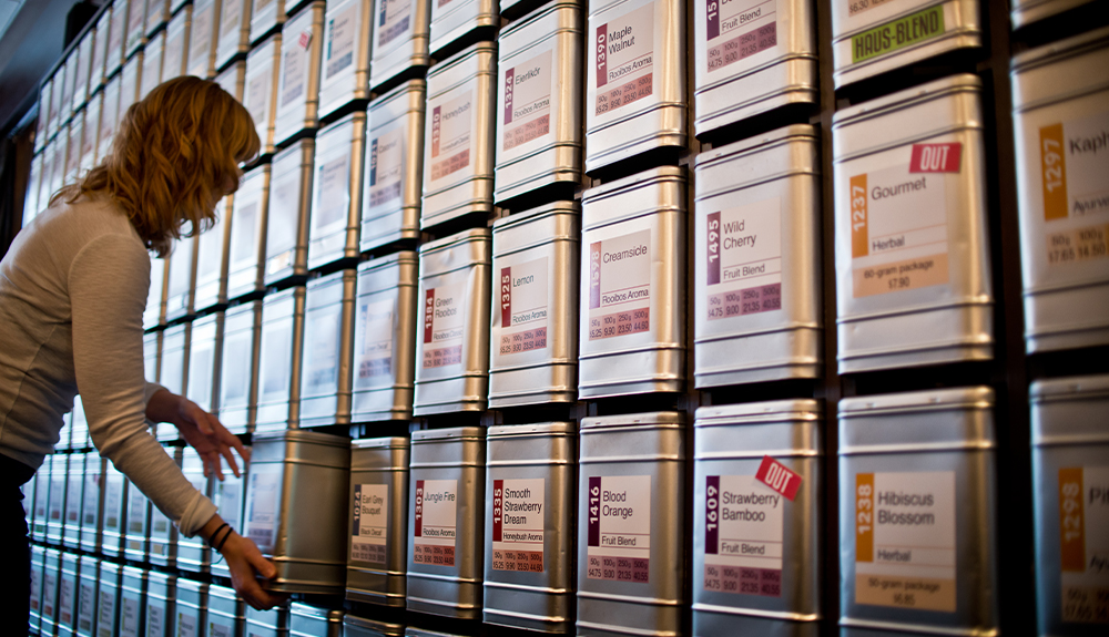 An employee chooses a tin from one of the 180 varieties of tea stacked on a wall at TeaHaus in Ann Arbor, Michigan.