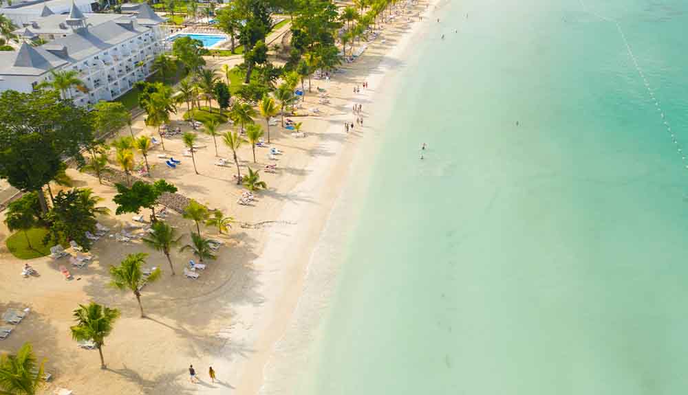 An overhead view of turquoise water and a white-sand beach in Negril, Jamaica