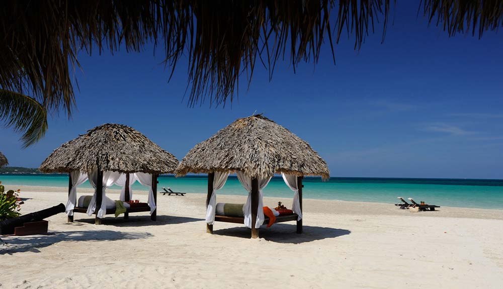 Palm-shaded beach huts on the ocean in Negril, Jamaica