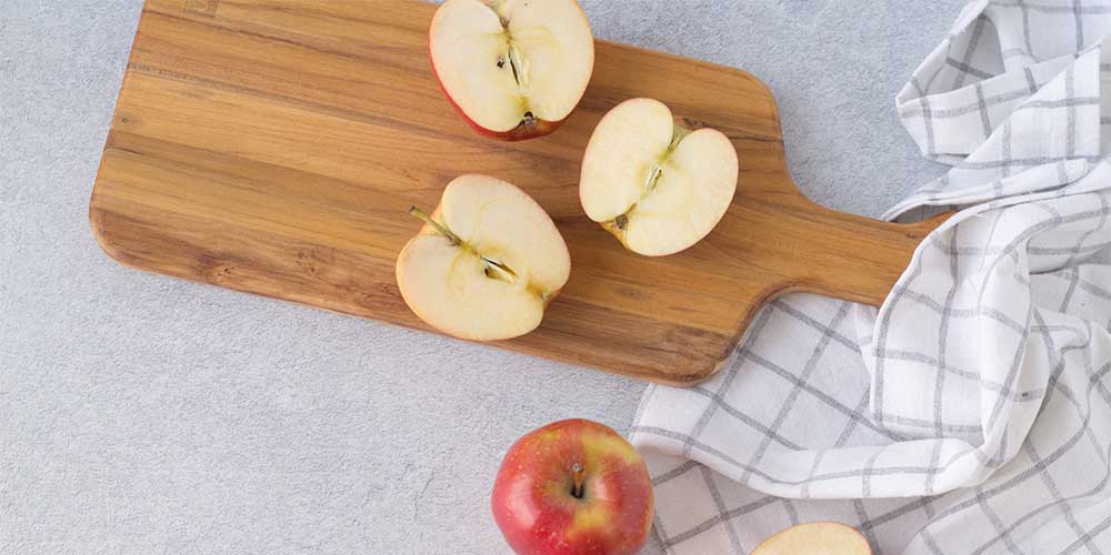 An overhead photo shows apples sliced in half on a cutting board