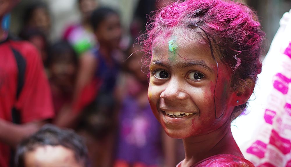 A child is shown with bright purple powder in her hair and on her face
