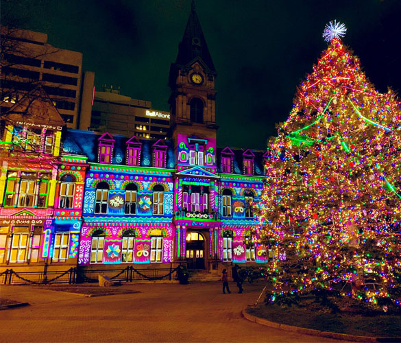 A winter village complete with a tall tree covered in rainbow-coloured lights, and a street lined with lit-up shops in bright colours.