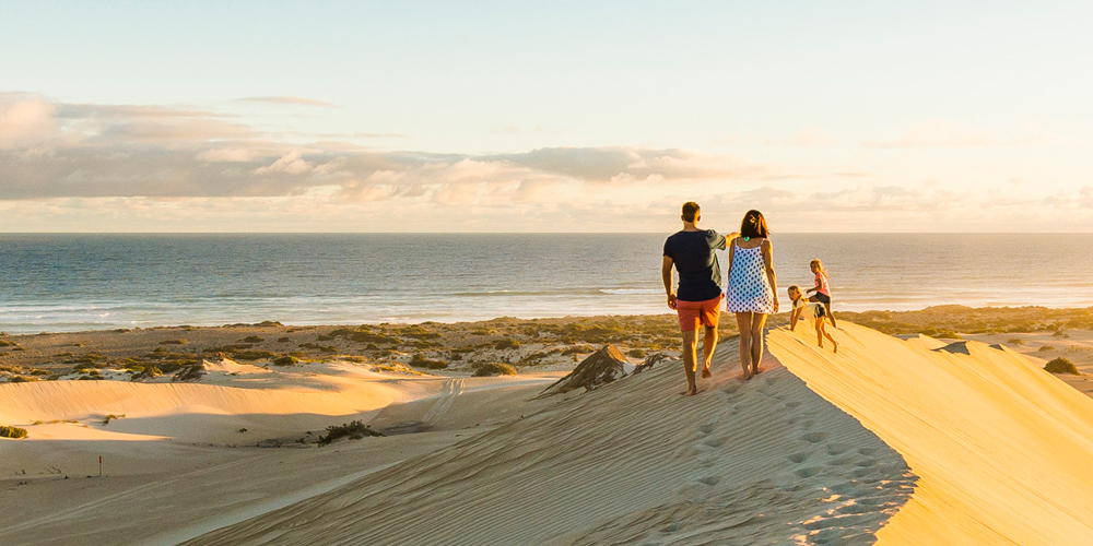 A couple walking on a sand dune at a beach