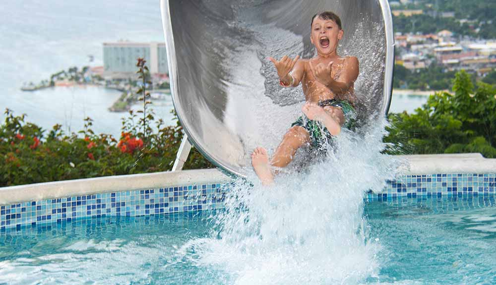 Young boy excited to reach the end of a water slide, about to drop into the pool