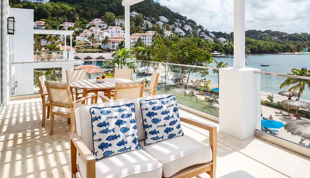 Outdoor couch with outdoor tables and chairs behind it on the balcony of the Windjammer Landing