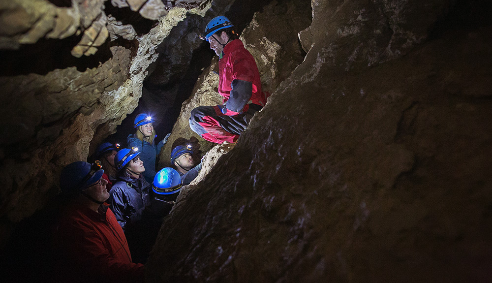 A group of people explore the dark caves at Horne Lake