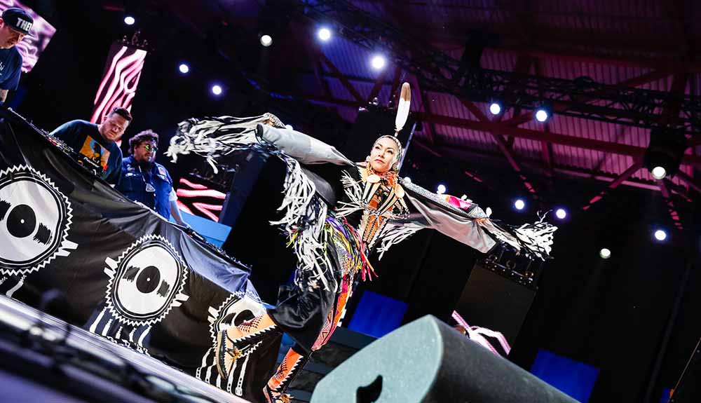 A woman in traditional Indigenous costume dances onstage at the Indigenous Arts Festival 