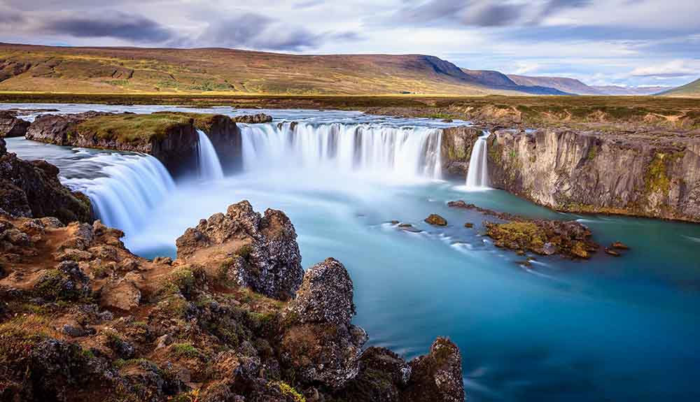 Godafoss falls stream into a pool of blue green water in Iceland