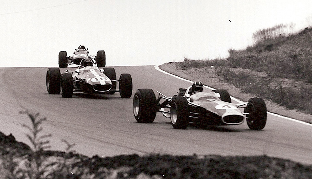 A black and white photograph shows three race cars speeding around a curve at the Canadian Grand Prix