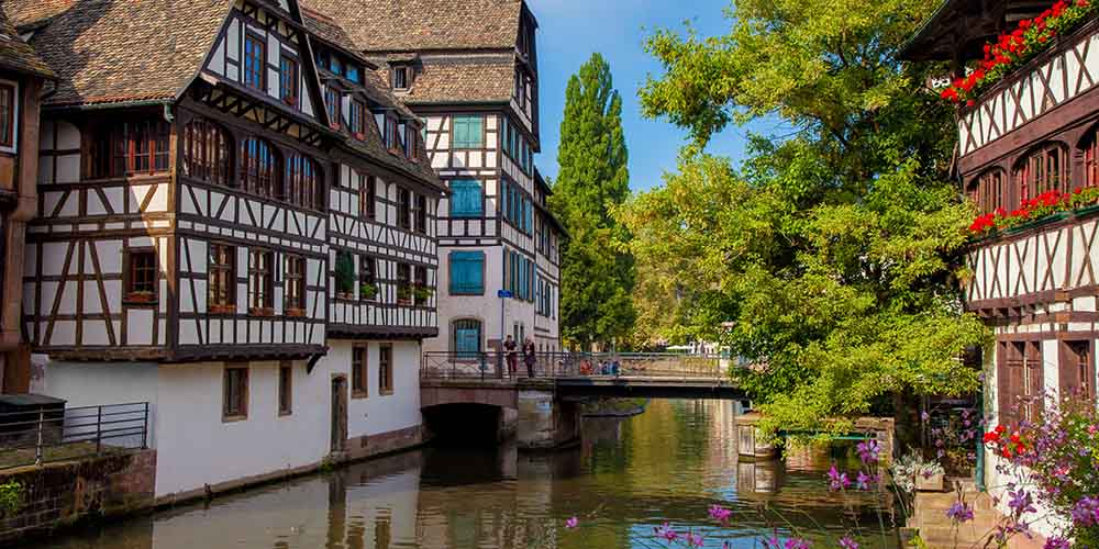 Cute buildings line a river in Strasbourg in the daytime