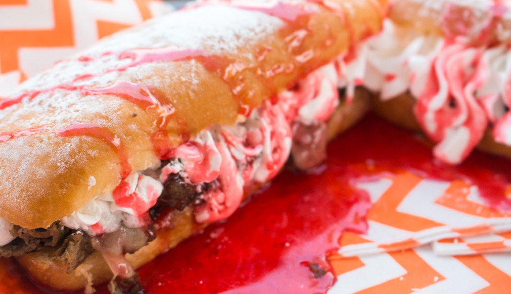 Steak sandwich with whipped cream and a large drizzle of strawberry sauce, as seen at the CNE