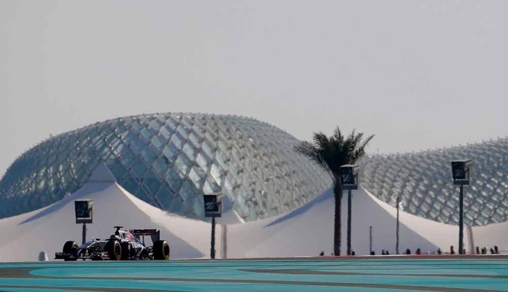 A Formula 1 car is seen in he distance in front of white tents and a circular building in Abu Dhabi, UAE