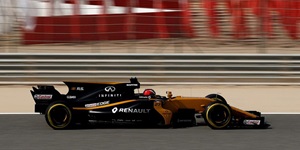 A black Formula 1 race car speeds down a track in Sakhir, Bahrain