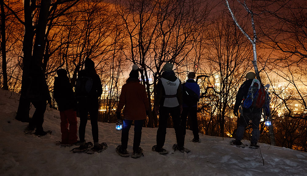 Couples wearing snowshoes and enjoying the views from a trail on Mount Royal