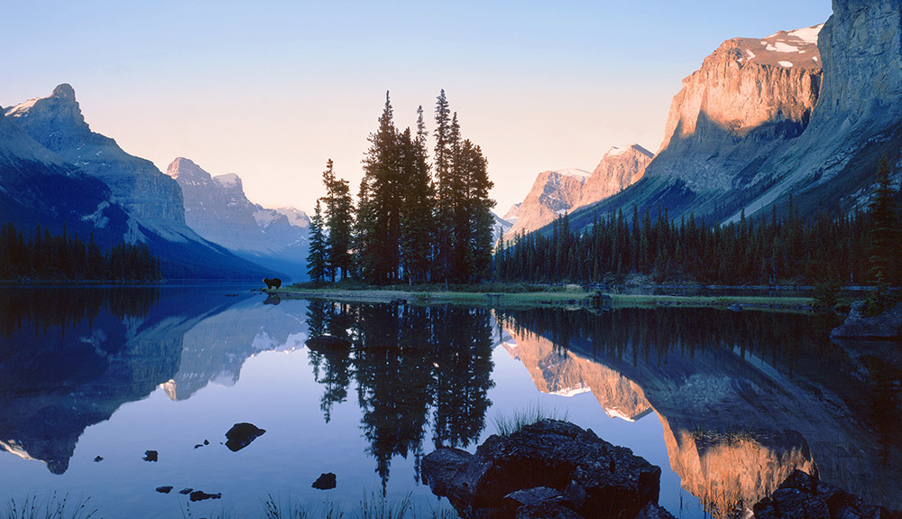 Beautiful landscape shot of mirror calm lake with the Rocky Mountains in the distance just before sunset