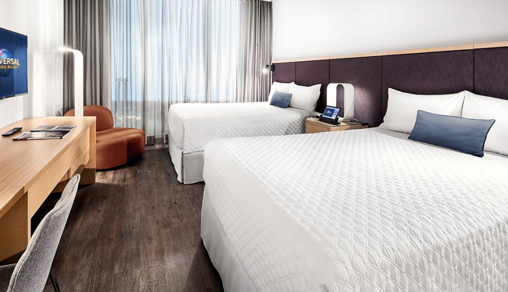 Two perfectly made beds with white linens are seen inside the clean and simple hotel rooms at the Universal Orlando Resort
