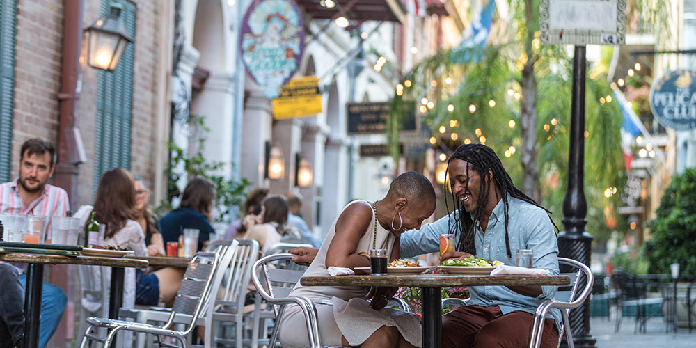 Couple laughs at their table on a busy patio in New Orleans