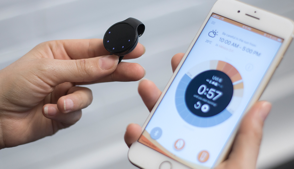 iPhone opened to a UV meter app with a wearable UV tracker attachment