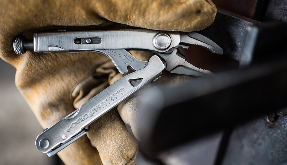 Gloved hand holding a multi-purpose Leatherman tool