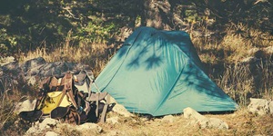 A tent and camping supplies in a remote area in the woods