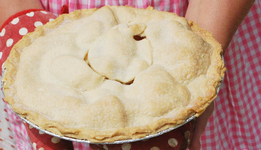 Hands holding a fresh apple pie