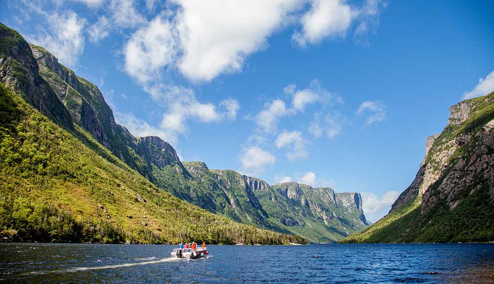 People on a boat enjoying a spectacular view as they float in Western Brook Pond