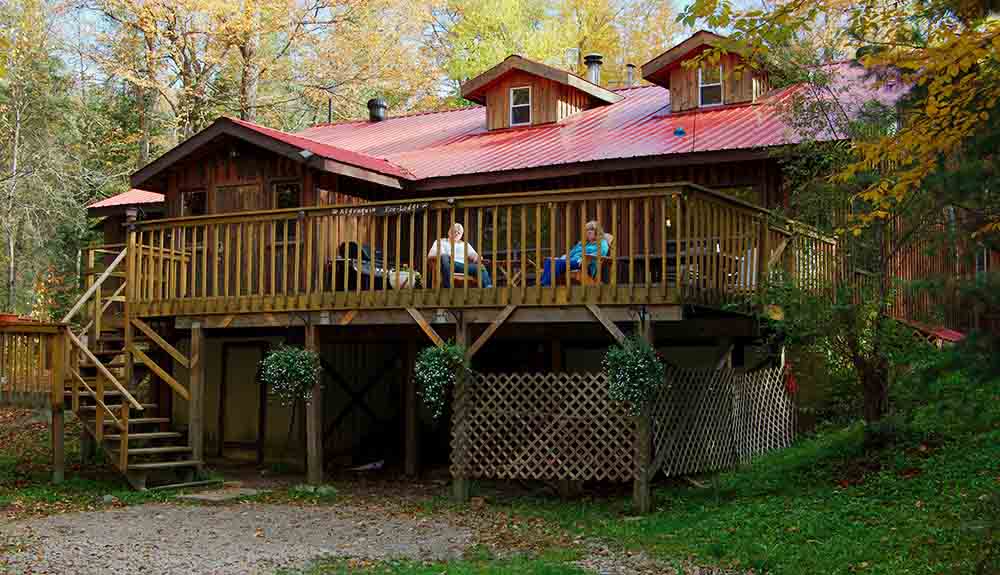 Large wooden Eco-Lodge at Algonquin Park, two older people look out at the woods from the outdoor deck